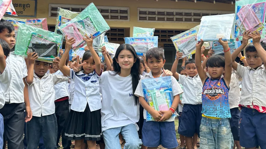 Kea Chhorita with students holding up their school supply kits on the Charity Tour